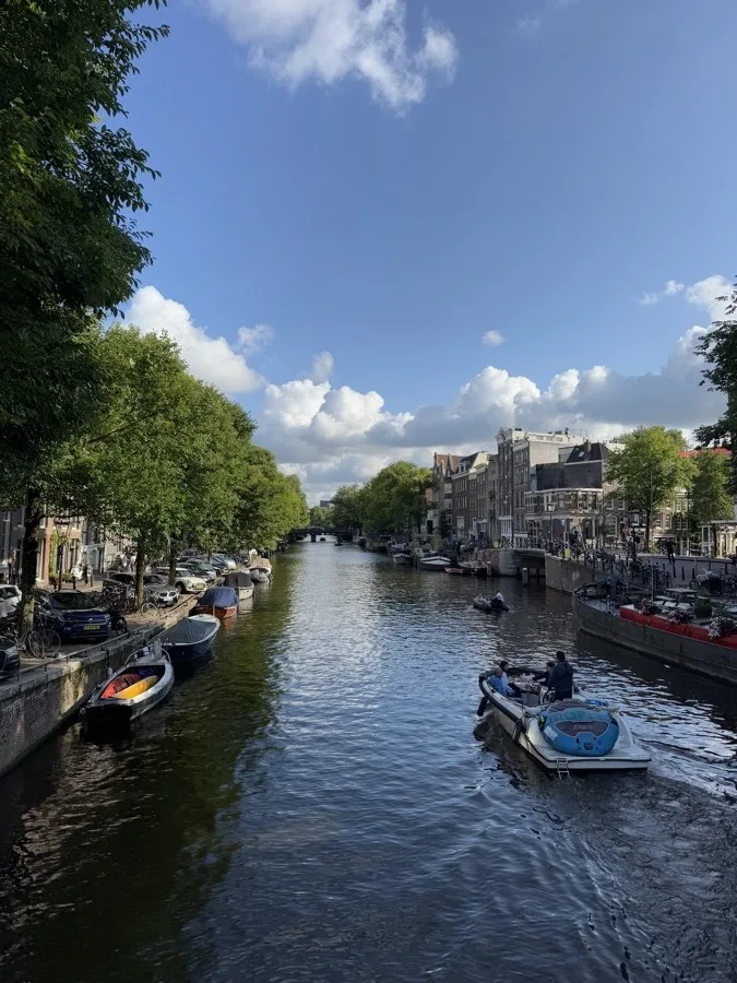 A canal in Amsterdam, moored boats along the quay and a small boat in the channel